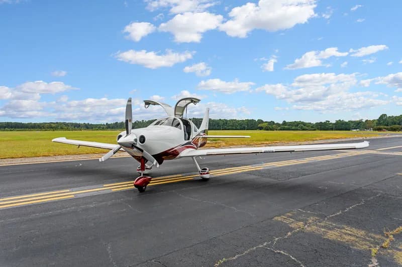 A Cirrus SR22 aircraft with doors open on the tarmac.
