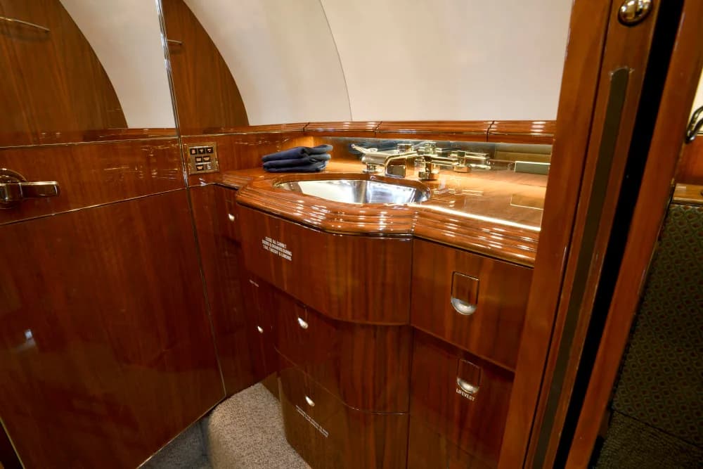 Aircraft lavatory with wood trim and a sink.