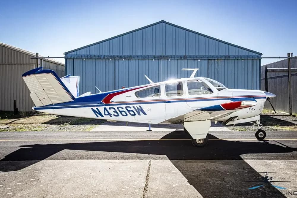 A Beechcraft Bonanza with registration N4366W is parked on the tarmac in front of a hangar.