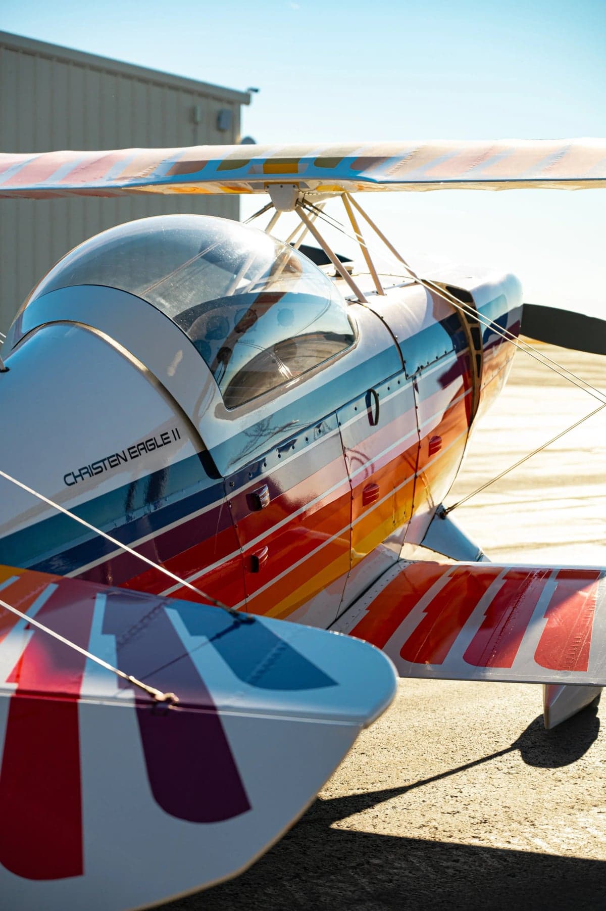 Close-up of the Christen Eagle II biplane showing the colorful paint scheme and cockpit.
