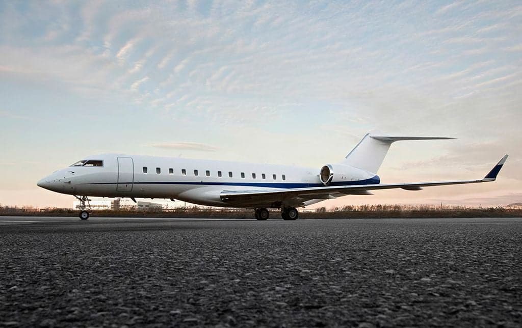A white Bombardier Global Express business jet on the tarmac.