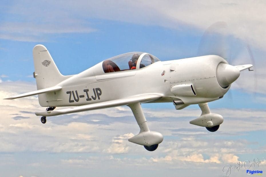 A white aircraft in flight against a cloudy sky.