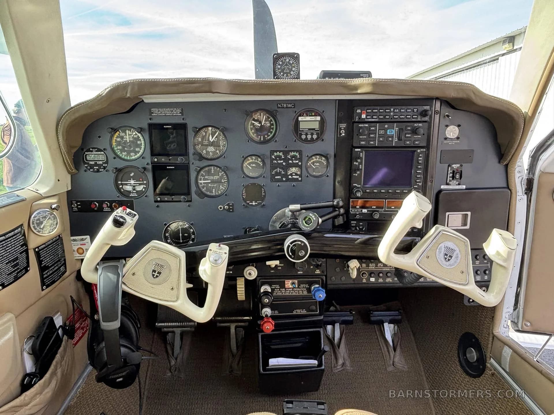 The cockpit of a small aircraft, featuring a complex instrument panel with analog gauges and digital displays, and two control yokes.