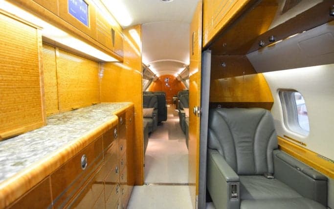 View of the aircraft's interior cabin with leather seats, cabinets, and wood trim.