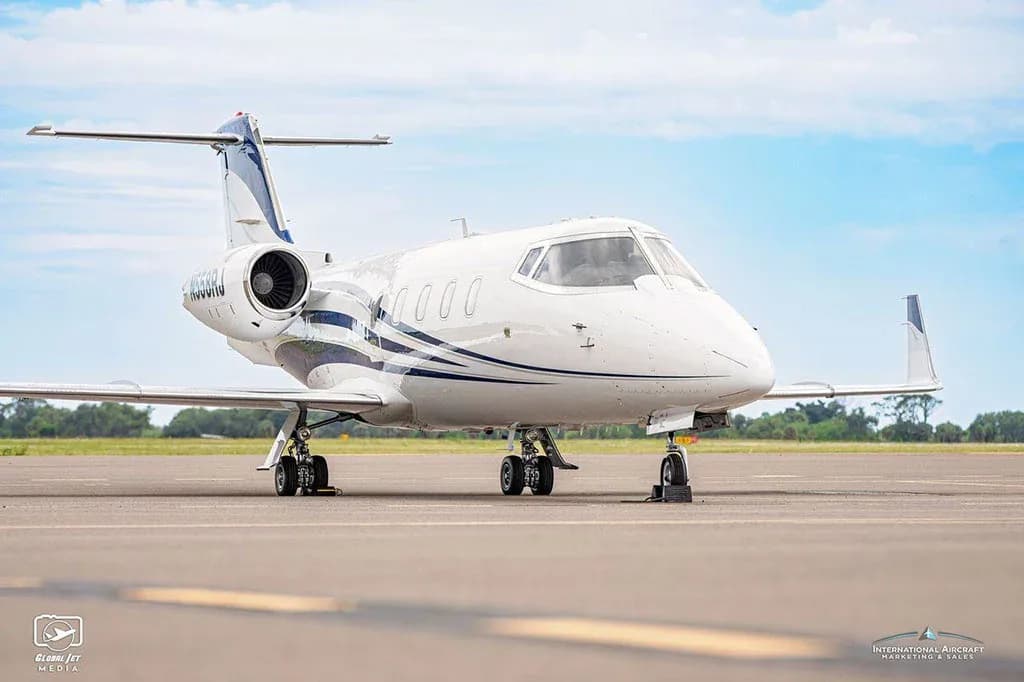 A front-quarter view of a white business jet with blue stripes, tail number N558RJ, parked on an airfield.