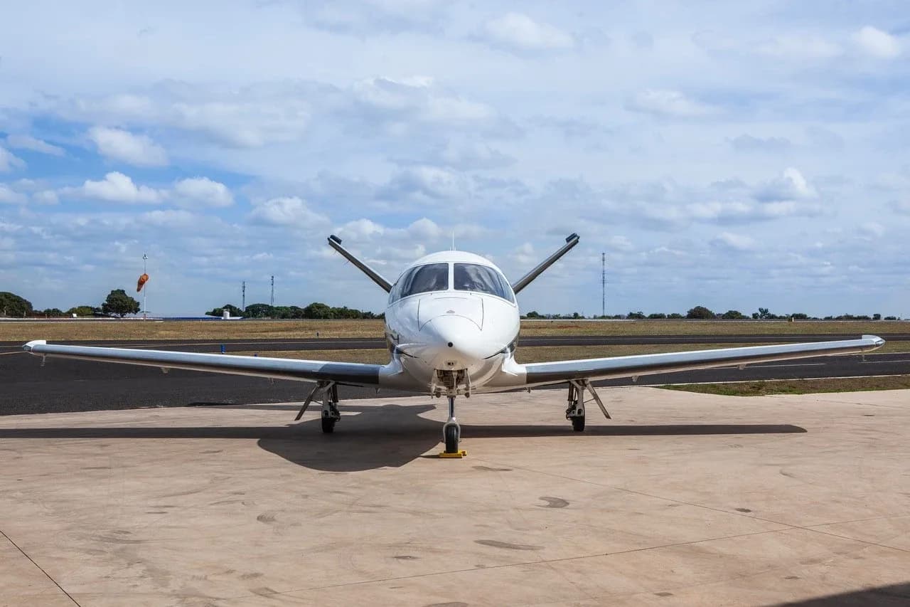 A head-on view of a white Cirrus Vision Jet with its wings extended, parked on an airfield.
