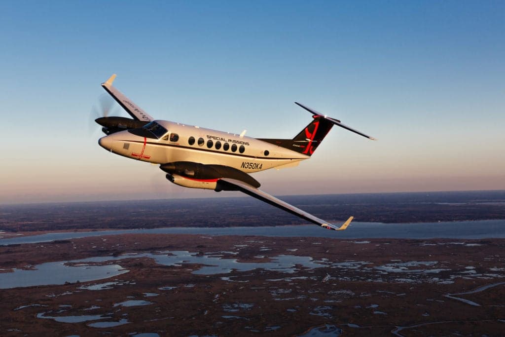 King Air 350 in flight over a marshy landscape.