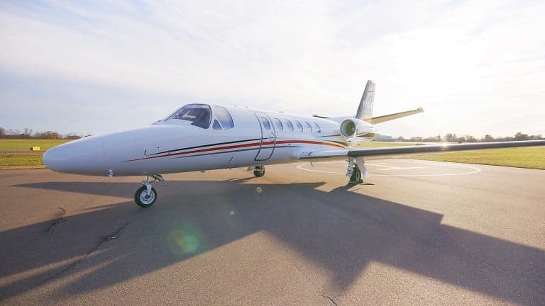 A Cessna Citation CJ4 sits on the tarmac in the sunlight.
