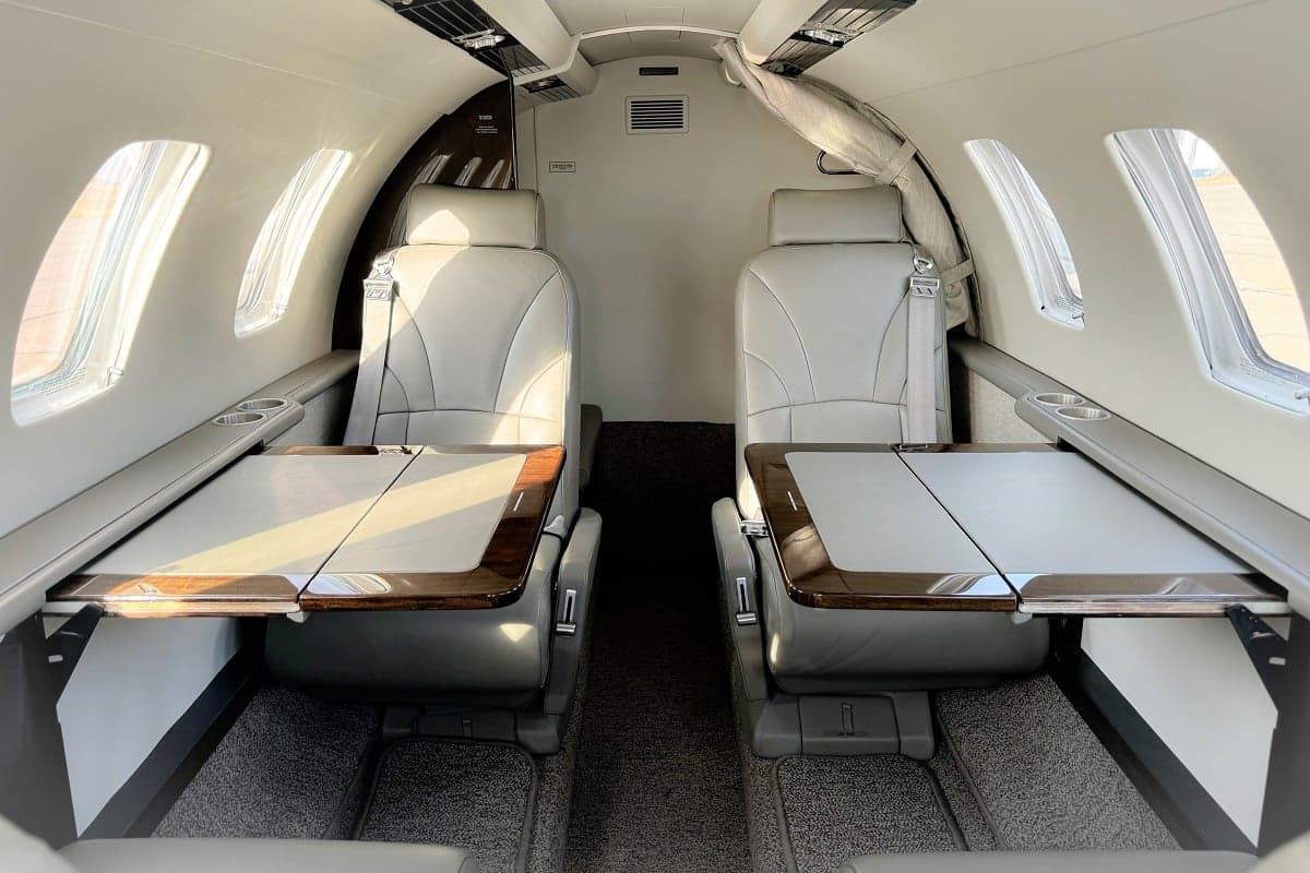 View of the interior of a Cessna Citation CJ3+ aircraft, showing the leather seats and fold-out tables.