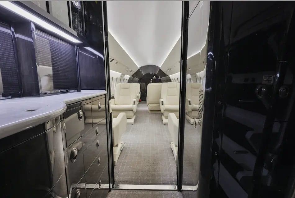 View down the aisle of the aircraft cabin with cream-colored seats.