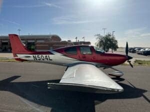 Side view of a Cirrus SR22T aircraft with a red and silver paint scheme, showing the registration number N504L.