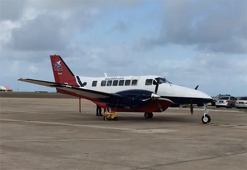 A red, white, and blue twin-engine turboprop aircraft parked on an airport tarmac.