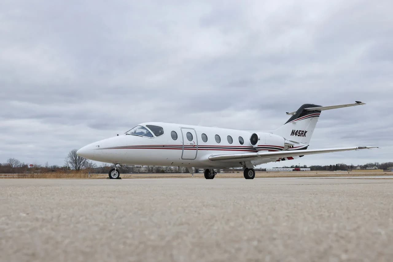 Side view of a white jet with red accents parked on the tarmac.