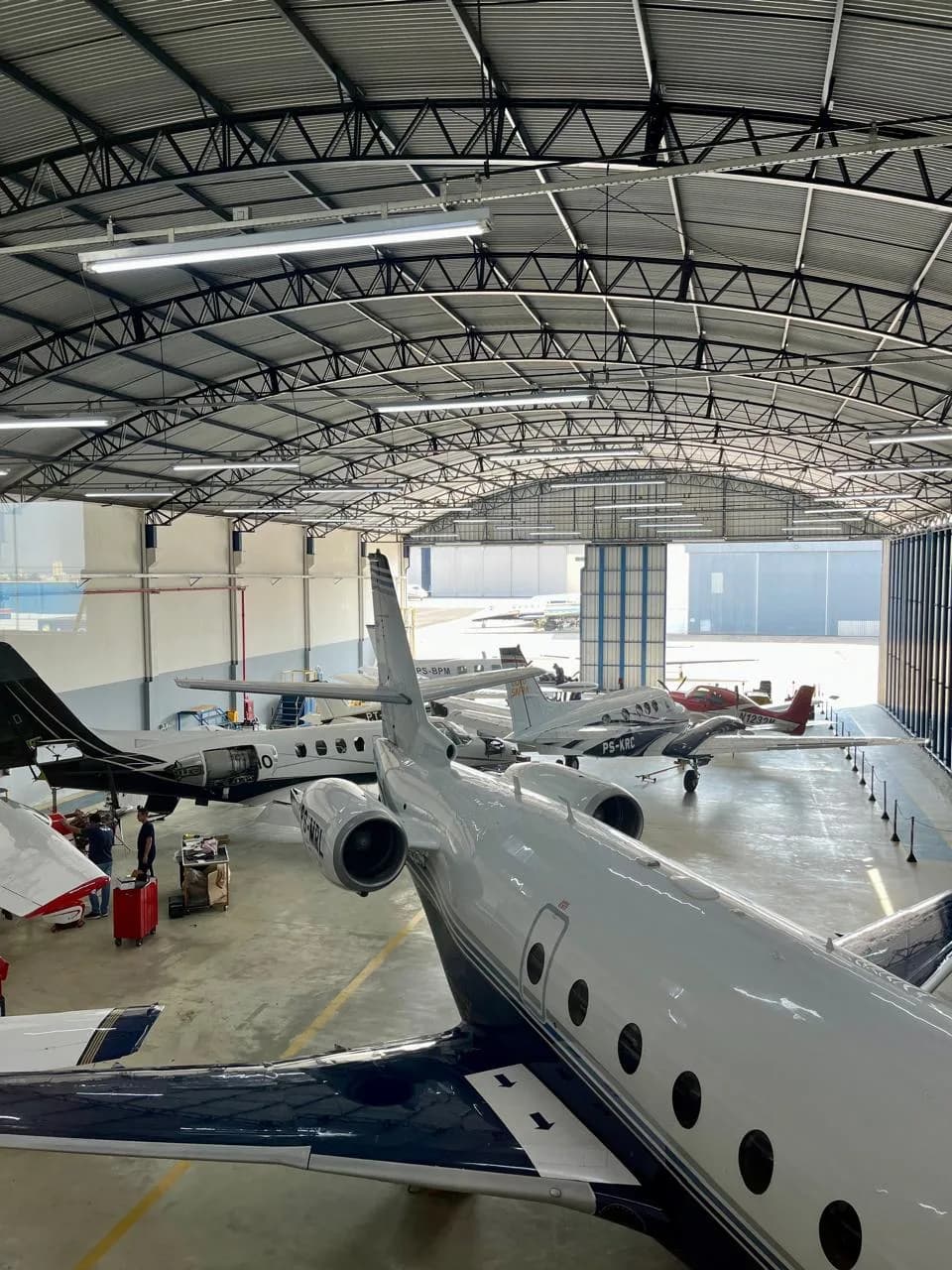 Multiple aircraft, including business jets, parked inside a large hangar.