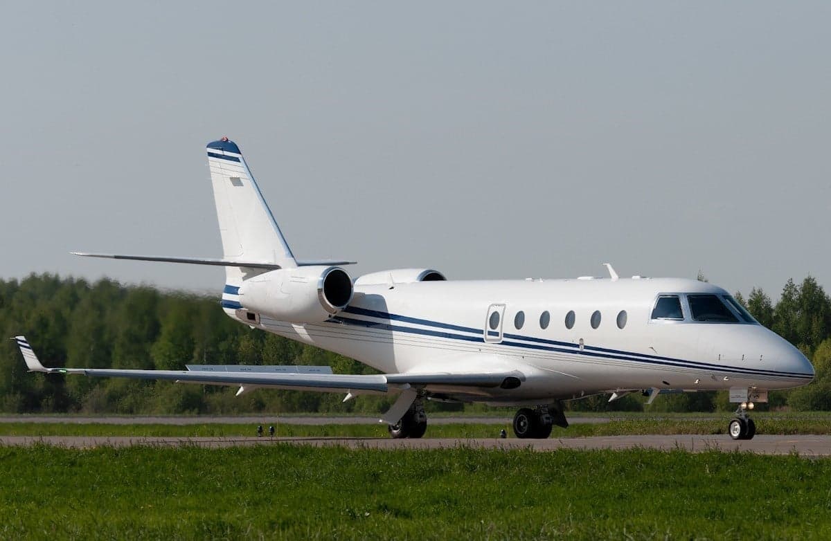 A white and blue Gulfstream jet on the runway.