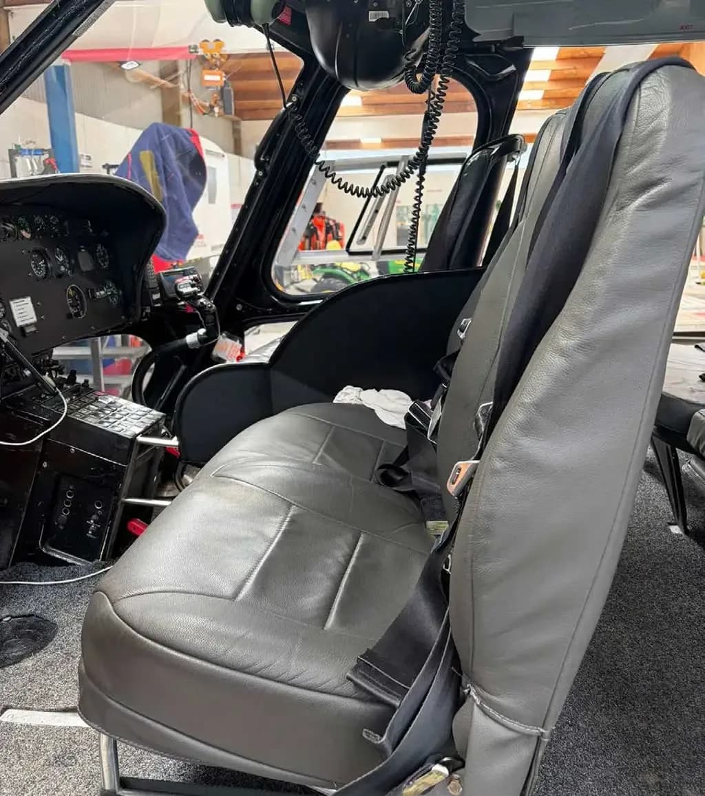 The grey front passenger seat and part of the pilot's instrument panel in a helicopter.