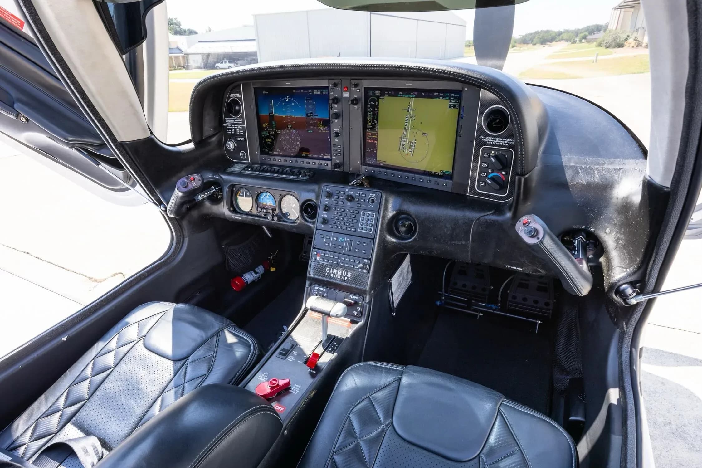 The cockpit of a Cirrus SR22 aircraft, featuring two large digital displays and black quilted leather seats.