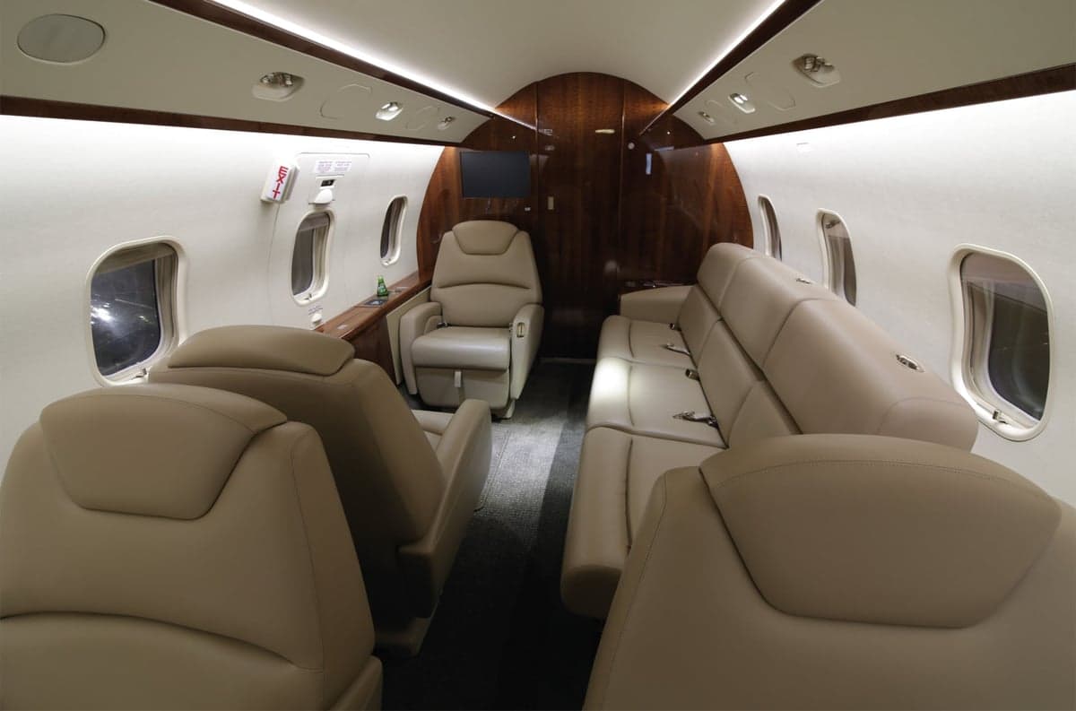 View of the aircraft interior with tan leather seats and wood trim.