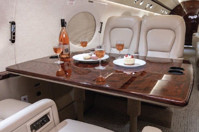 Interior view of the aircraft with a table set with wine and desserts.
