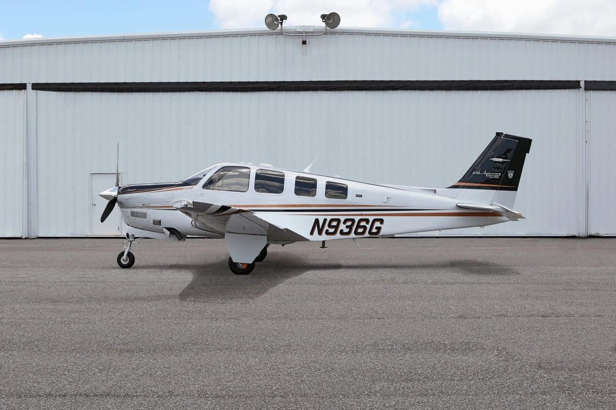 Side view of a Beechcraft Bonanza aircraft with tail number N936G parked in front of a hangar.