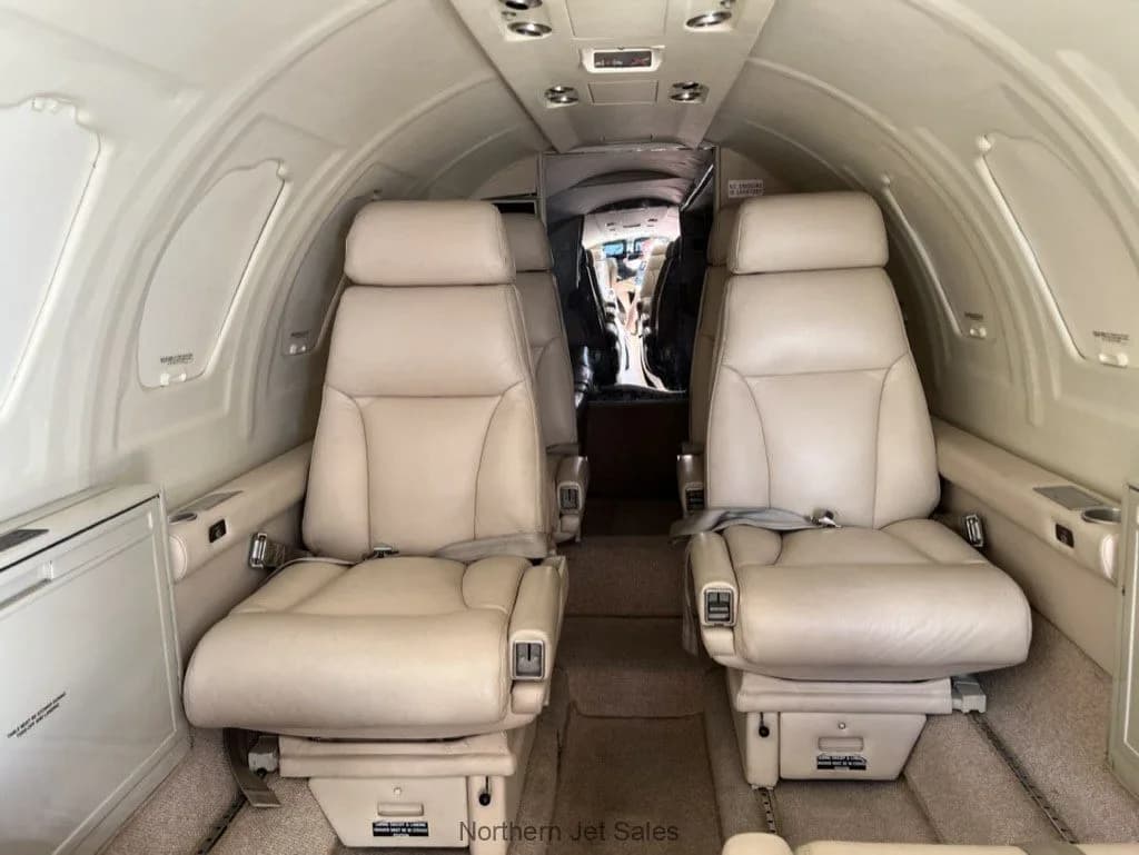 Interior view of the cabin of a jet with beige leather seats.