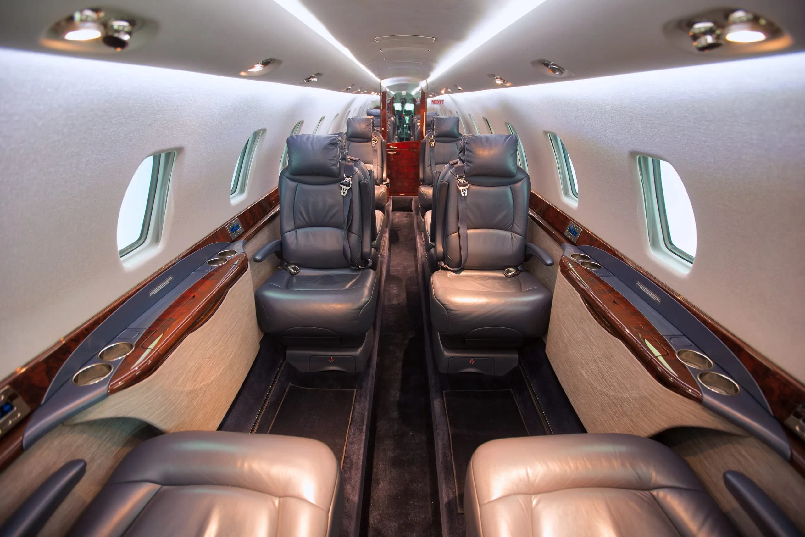 A view of the aircraft cabin with leather seats and wood trim.