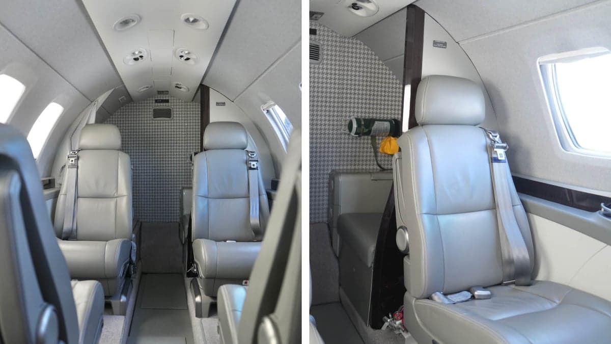 The interior of the aircraft shows gray leather seats and patterned wall coverings.