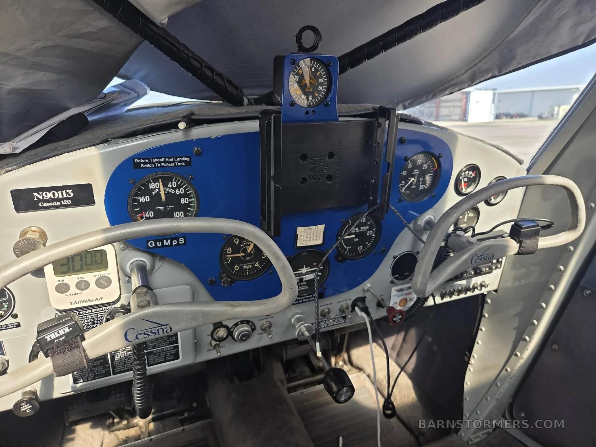 The blue and gray instrument panel of a Cessna 120 aircraft, showing various gauges and controls.