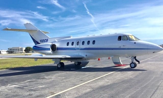 Side view of a white and blue aircraft on the tarmac.