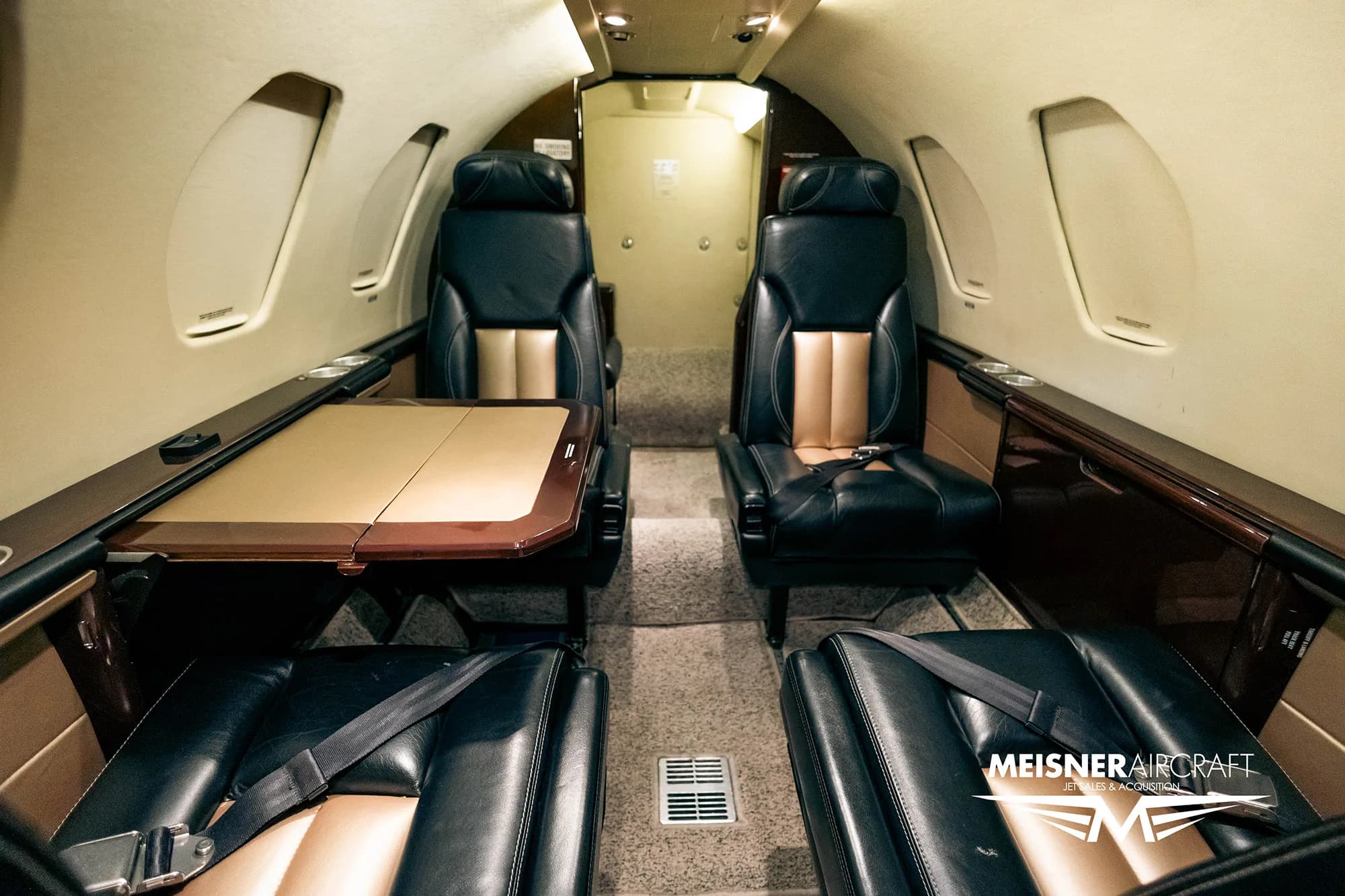 View of the aircraft interior from the rear, showing seats and table.