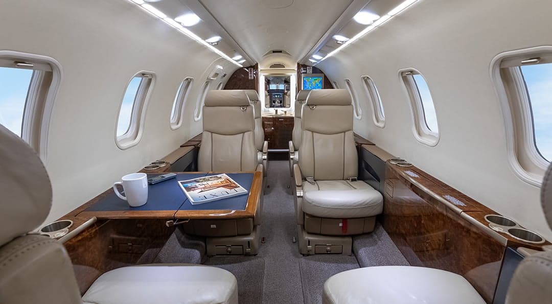 View of the Learjet 45XR cabin with leather seats and a table.