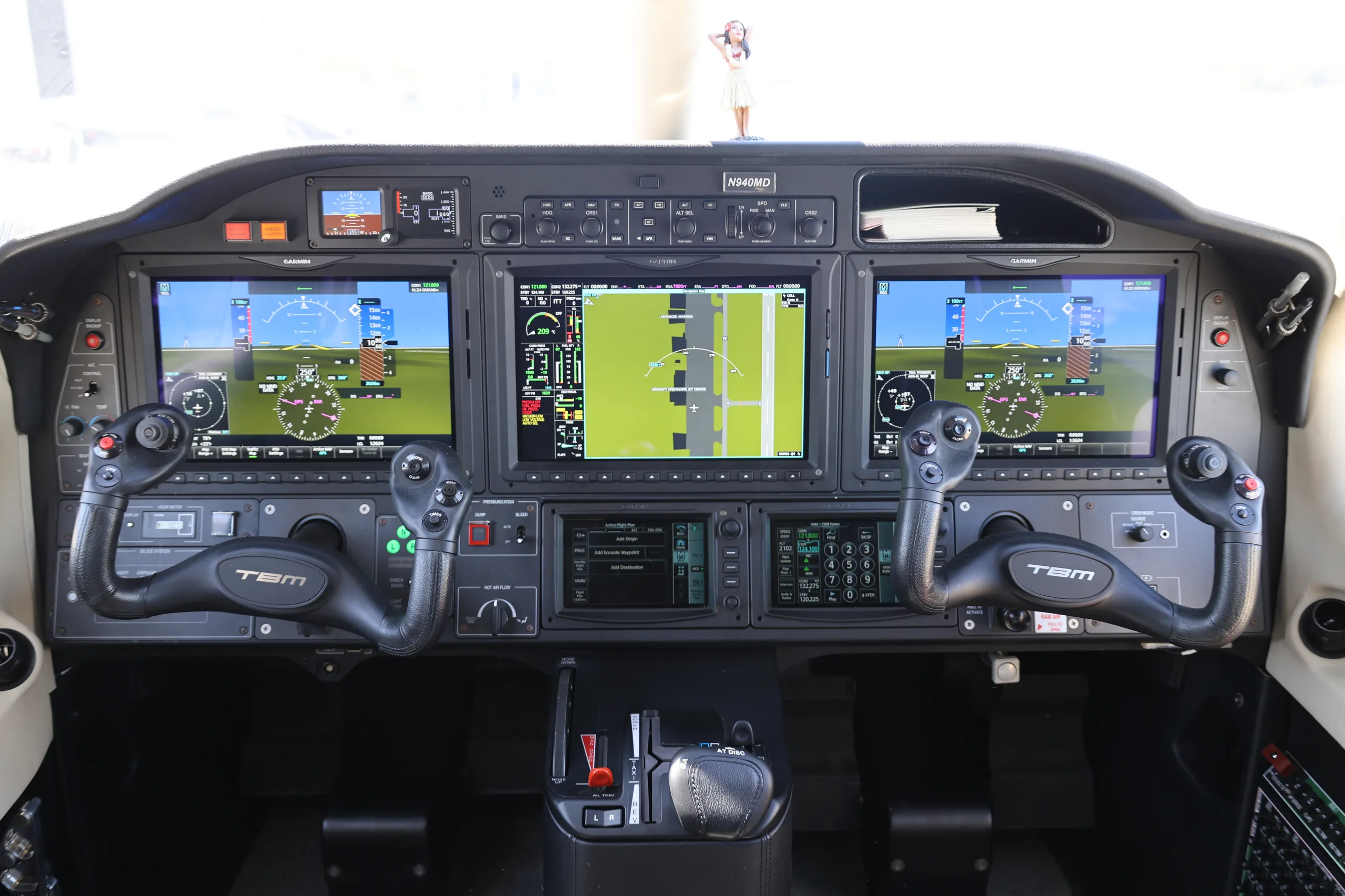 A wide view of the TBM 940 cockpit showing the instrument panel with active display screens and control yokes.