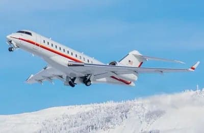 A Bombardier Global Express aircraft takes off over a snowy landscape.
