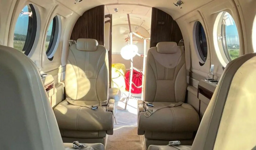 The aircraft's interior cabin with beige leather seats and windows, looking towards the rear.
