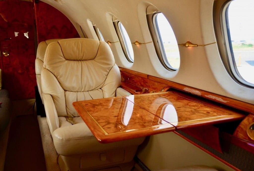 Interior of the aircraft with a leather seat and wooden table.