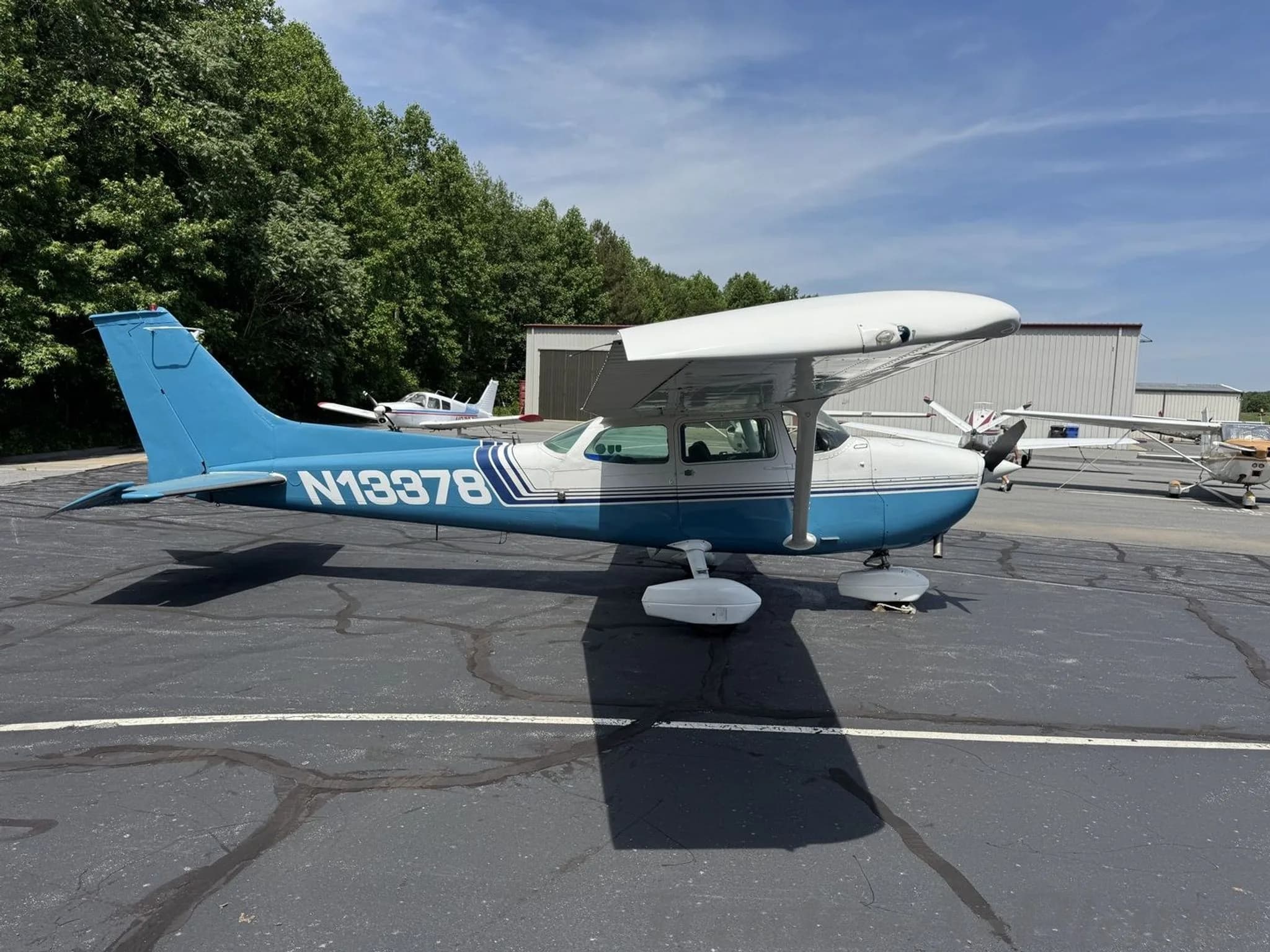 A side-right view of the blue and white Cessna 172 Skyhawk (N13378) parked on an asphalt apron.