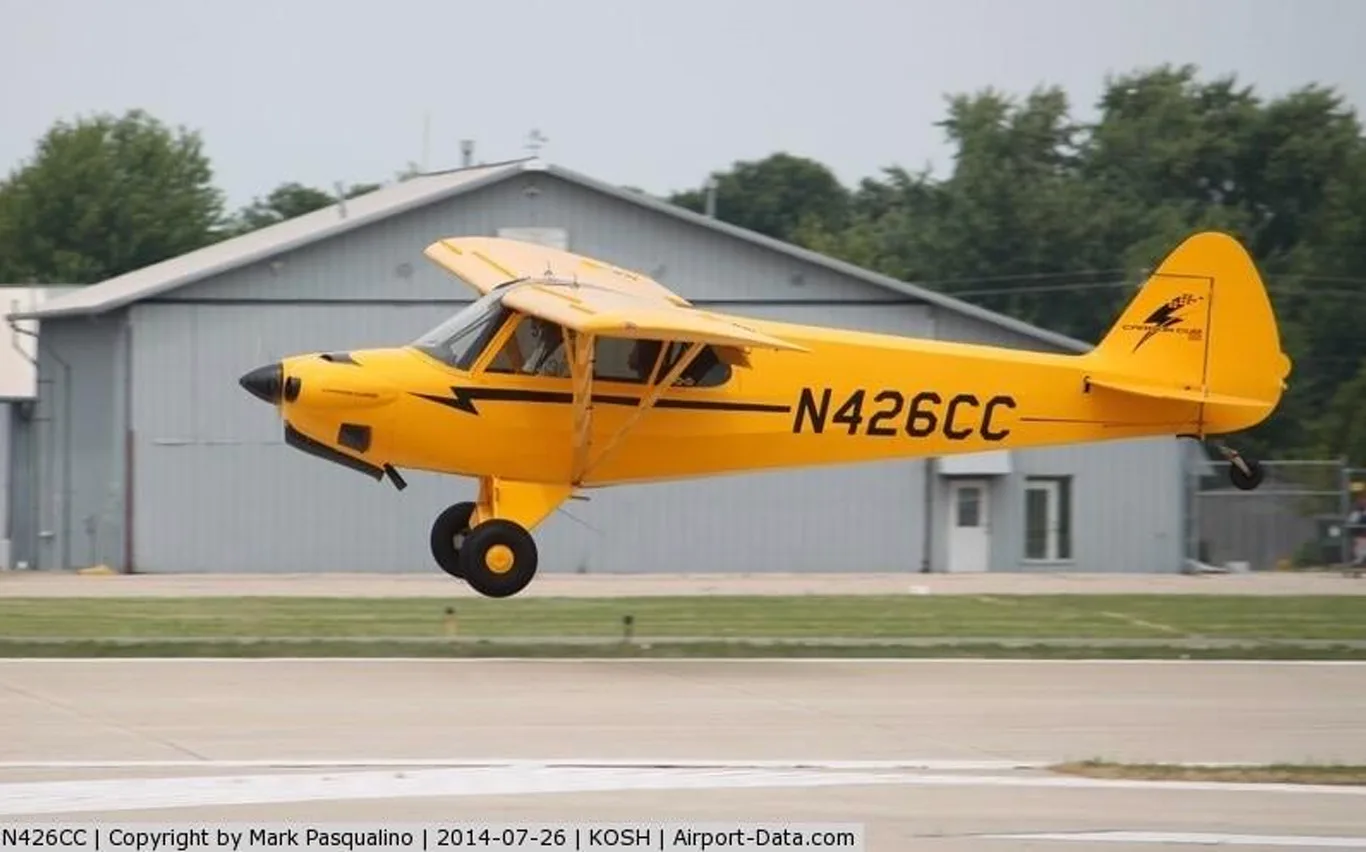 A yellow Carbon Cub aircraft, registration N426CC, taking off from a runway.