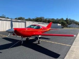 A red aircraft with registration N54JX parked on the tarmac.