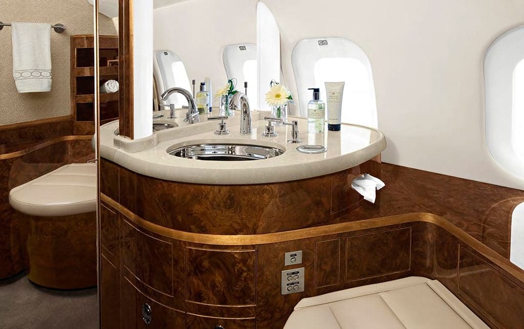 An aircraft lavatory with a sink, mirror, and wood accents.
