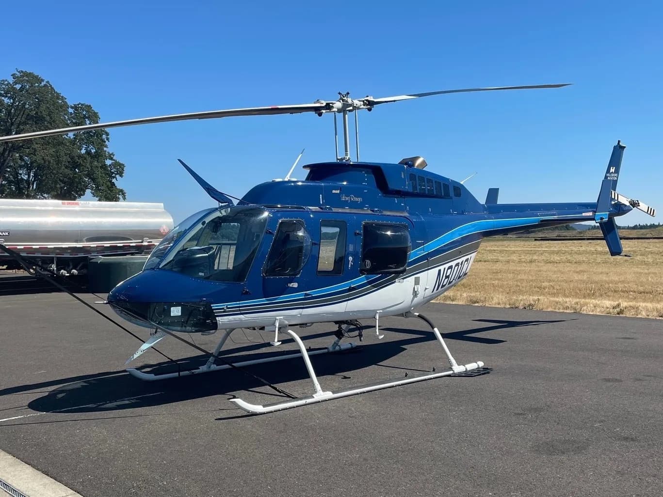 Bell 206B Jet Ranger with blue and white paint scheme, parked on the tarmac.