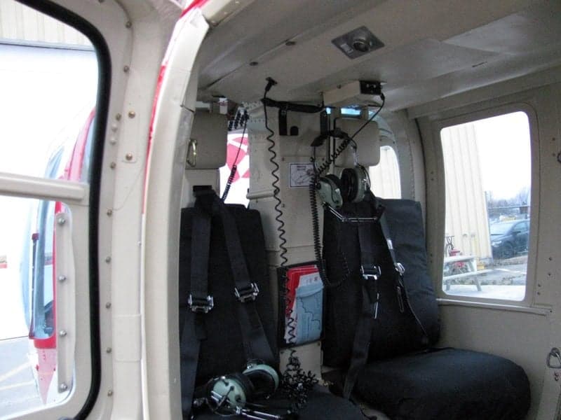 Interior view of the Bell 407 helicopter cabin with seats and headsets.