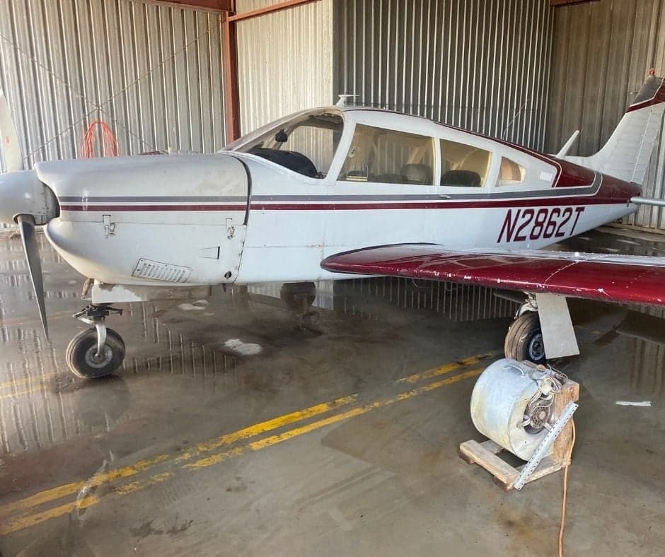 A white and red aircraft with tail number N2862T parked in a hangar.