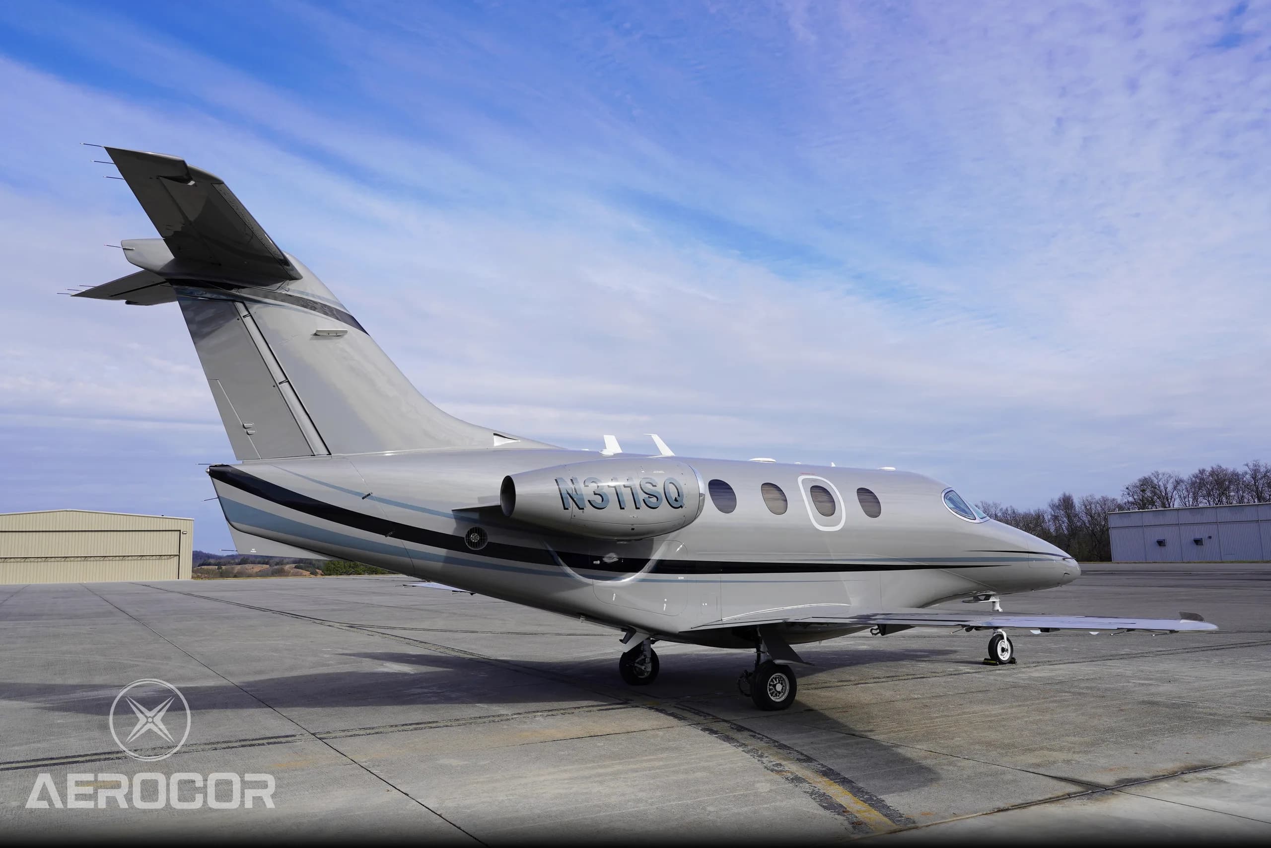 A rear-side view of the gray Raytheon Premier I business jet, registration N311SQ, on a sunny day.