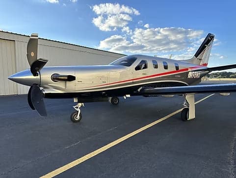 A TBM 930 aircraft with a silver and gray paint scheme is parked on the tarmac.