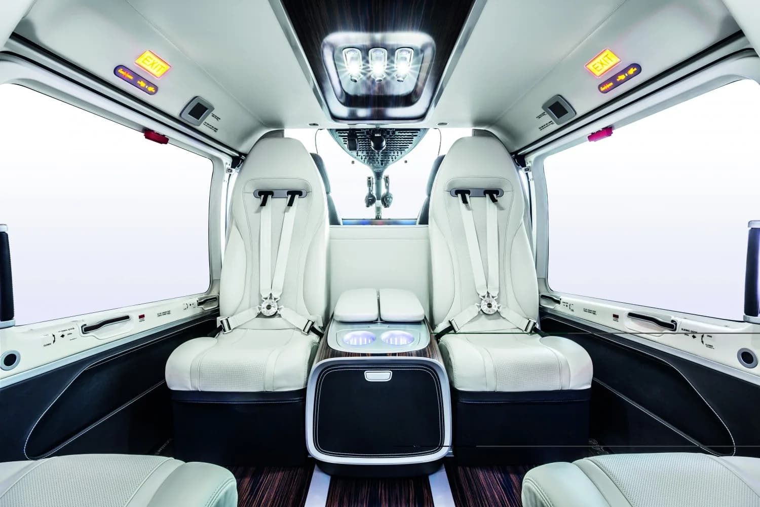 The luxurious white leather interior cabin of a helicopter with two passenger seats and a central console.