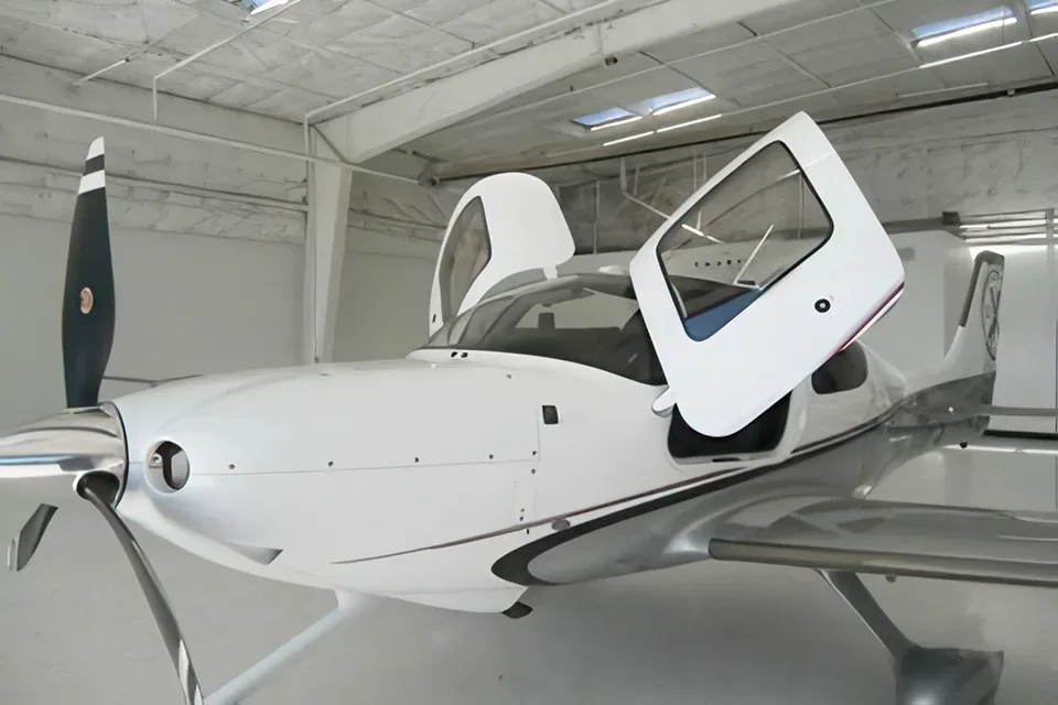 Cirrus aircraft with gull-wing doors open in a hangar.