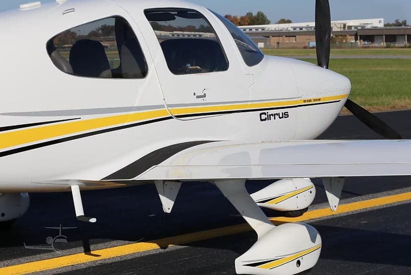 Close-up of the front side of a Cirrus SR22 aircraft, showing the Cirrus logo and paint scheme.