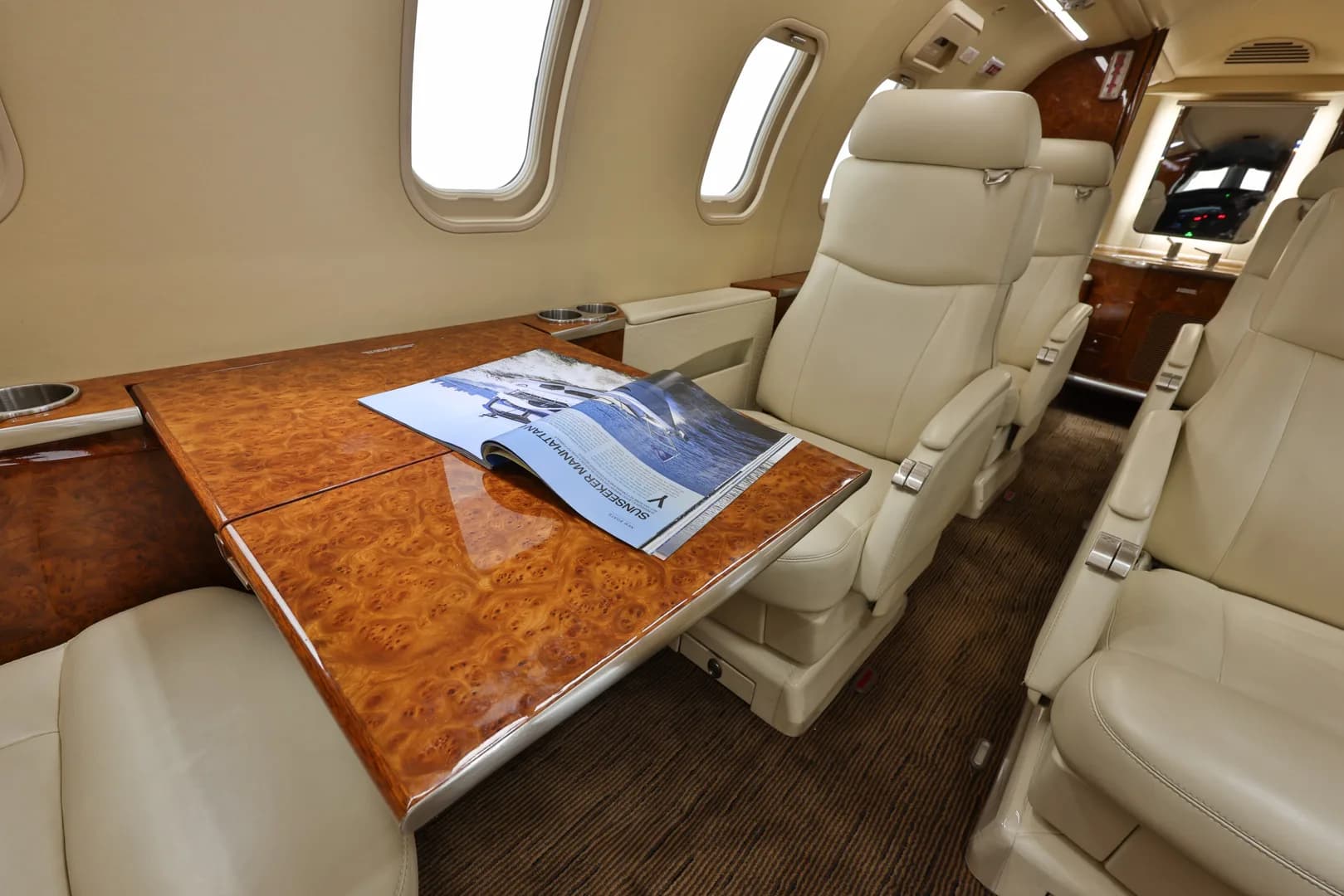Close-up of the cream-colored seats and wood table with a magazine.