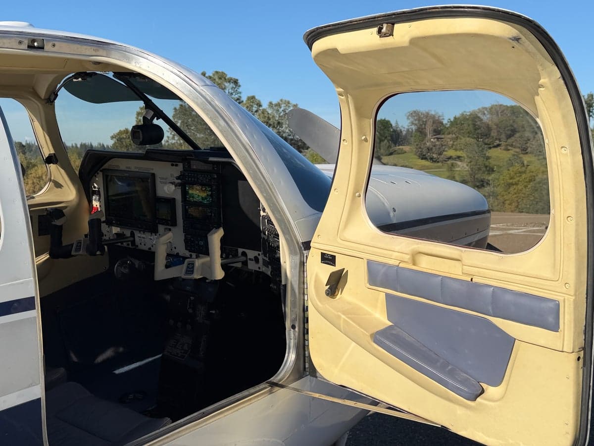 View into the Mooney M20J cockpit from the open door, showing the instrument panel and interior details.