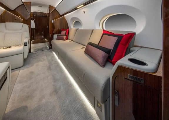 Aircraft interior with a couch and cream-colored leather seats.